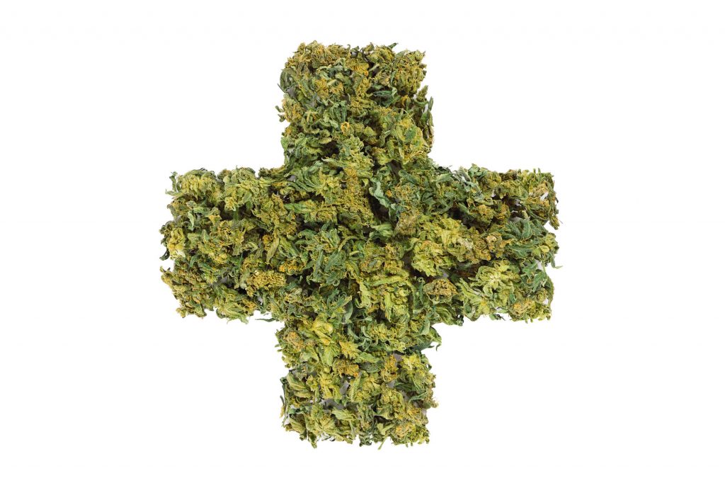 "Medizinkreuz" aus Cannabisblüten auf weißem Grund.